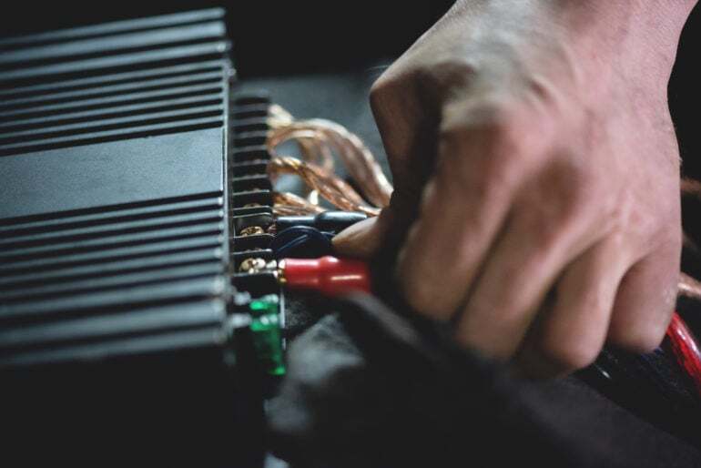 A hand connects wiring to the back of a radio receiver.